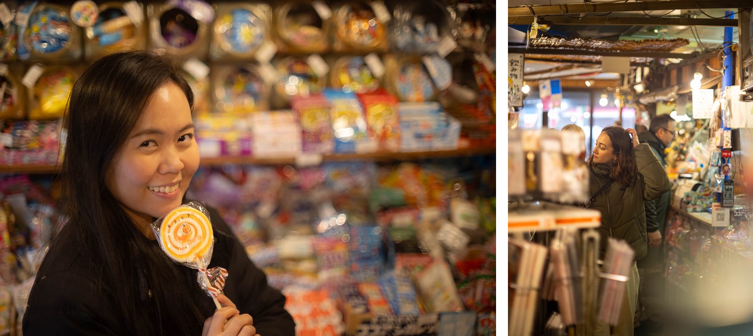 A woman posing in with a candy in a vintage candy store. Another woman browsing the candy store.