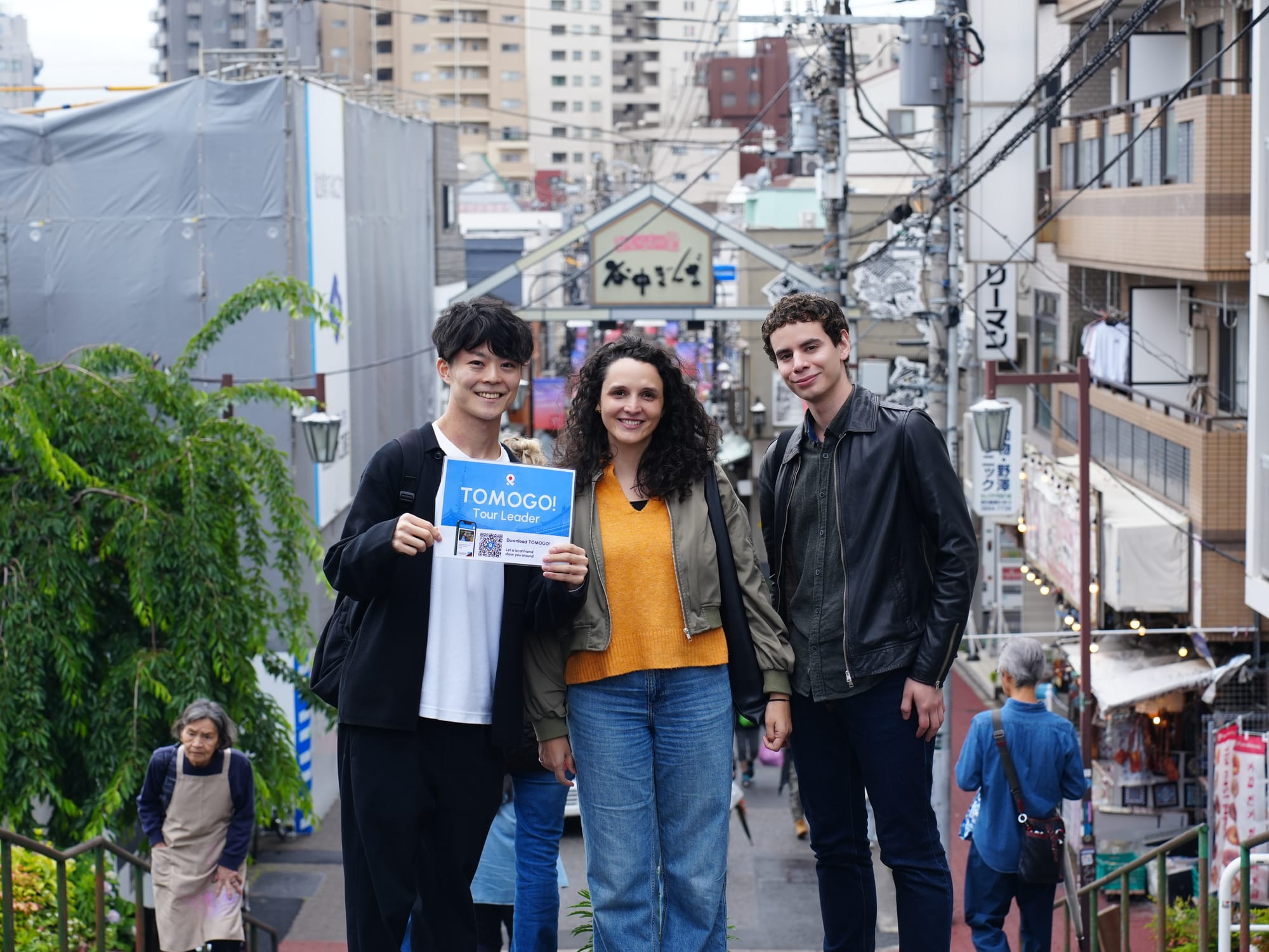 A TOMOGO! tour guide and guests posing in front of the Yanaka Ginza sign