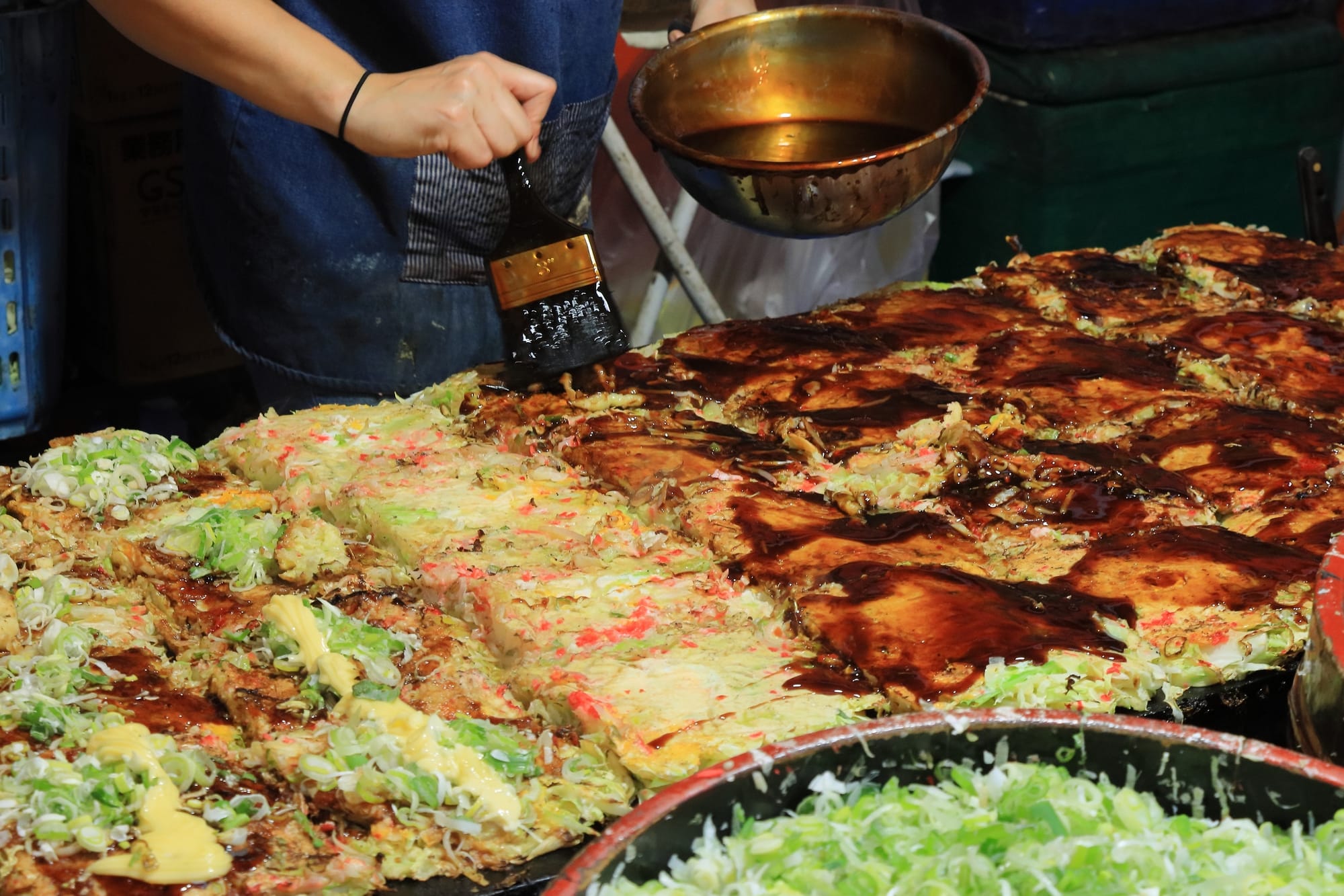 A chef preparing okonomiyaki (a type of savory Japanese pancake)