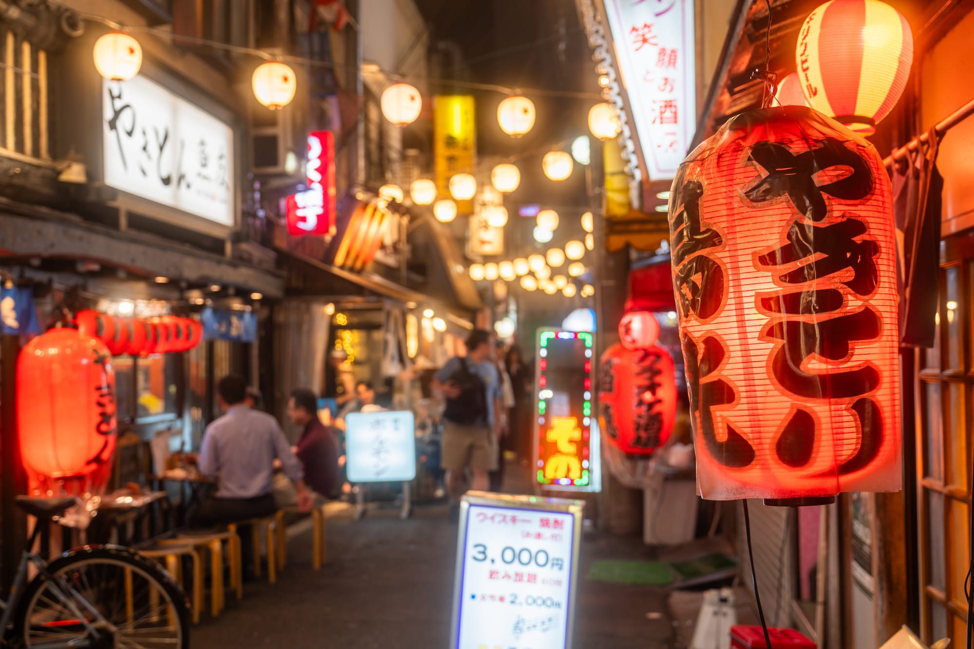 Night photo of a brightly lit street in Japan filled with bars and pubs