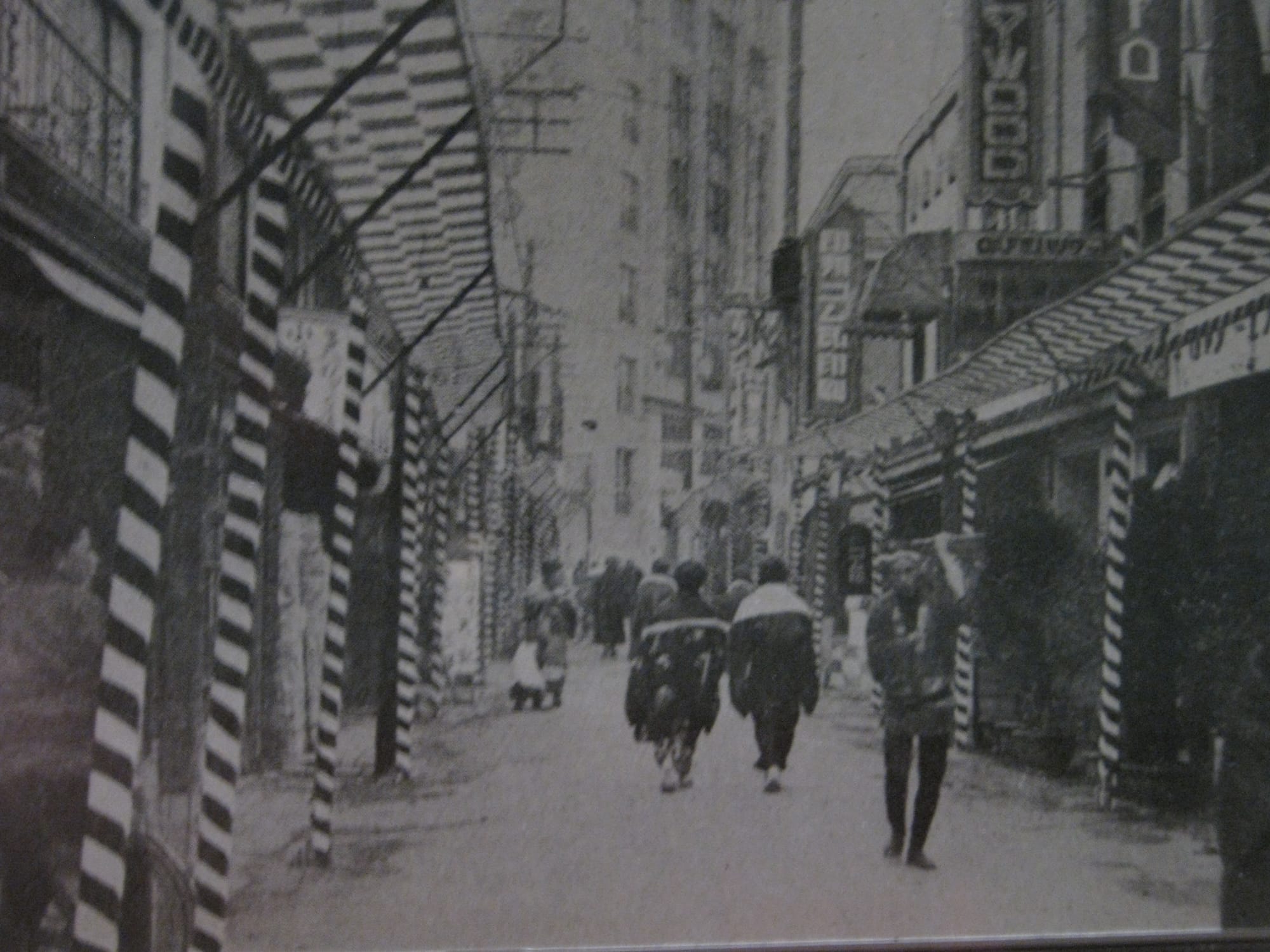 A black and white photo of Golden Gai with people walking the streets
