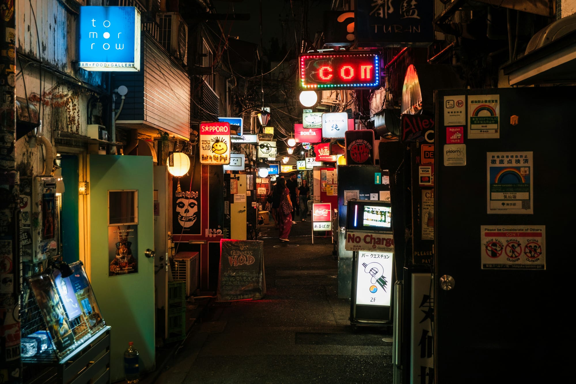 A narrow alleyway in Tokyo lined with neon-lit signs