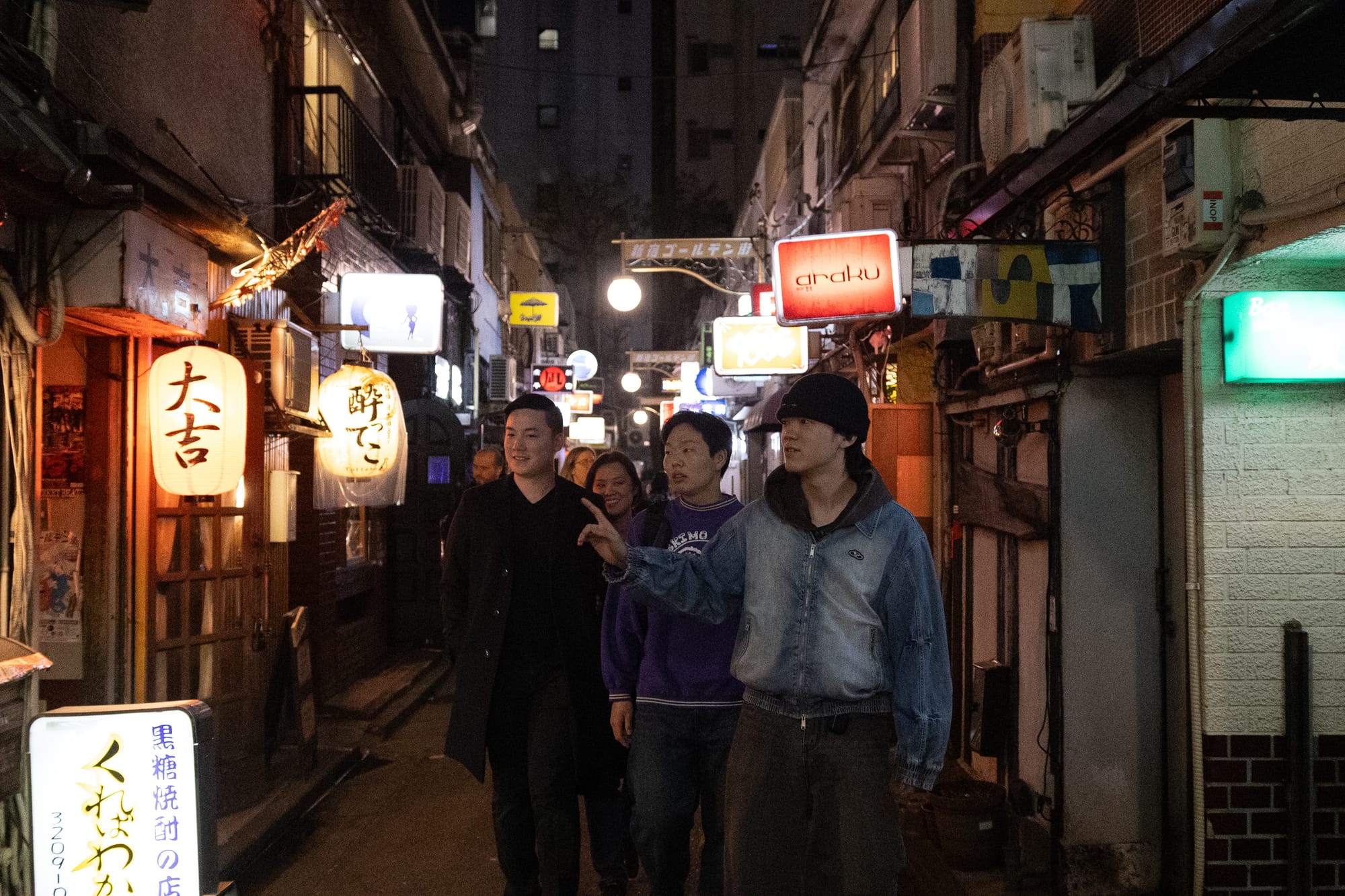 A group tour walks through the neon lit alleys of Shinjuku's Golden Gai