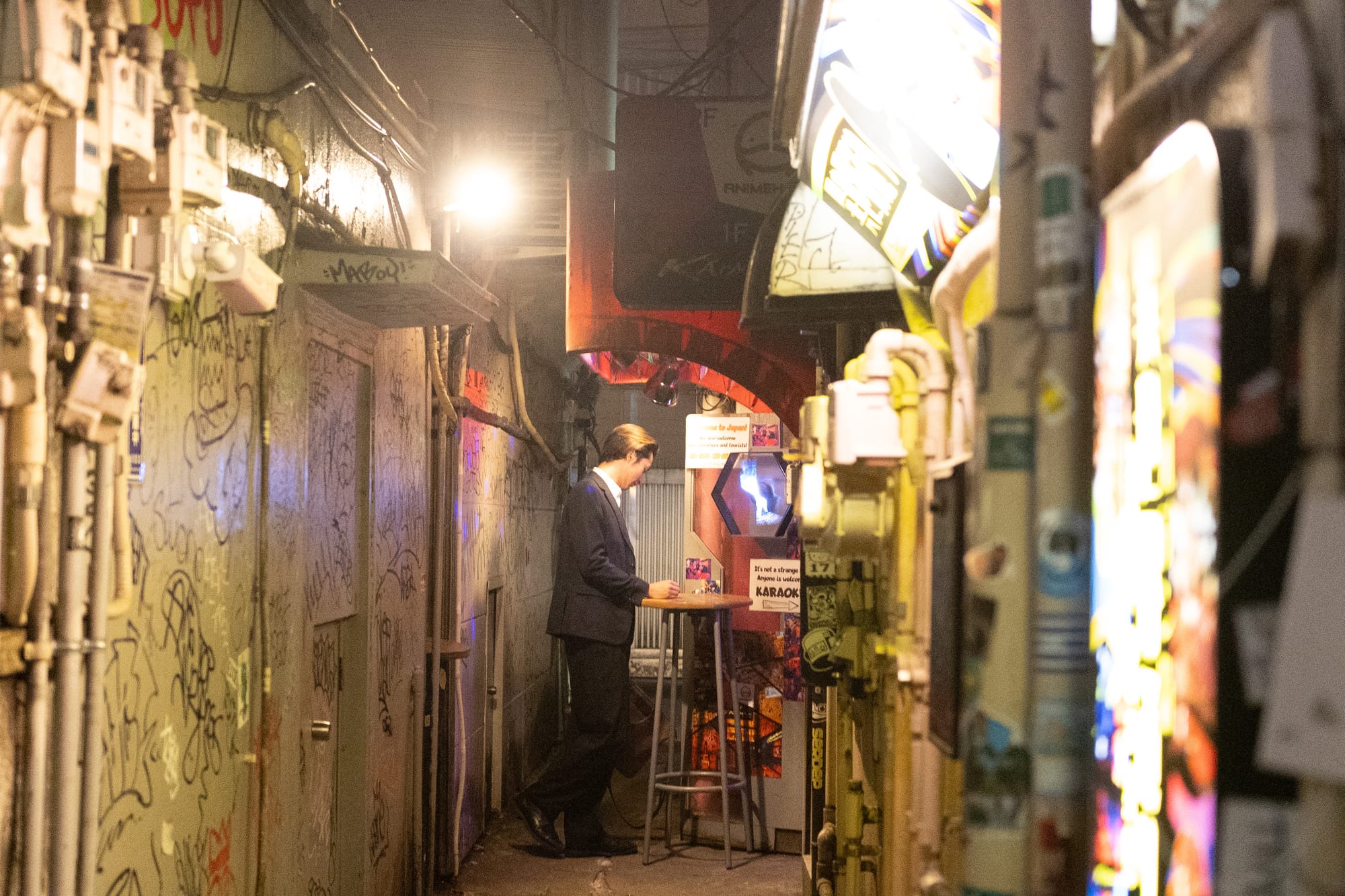 A Japanese salary man standing in a narrow alleyway