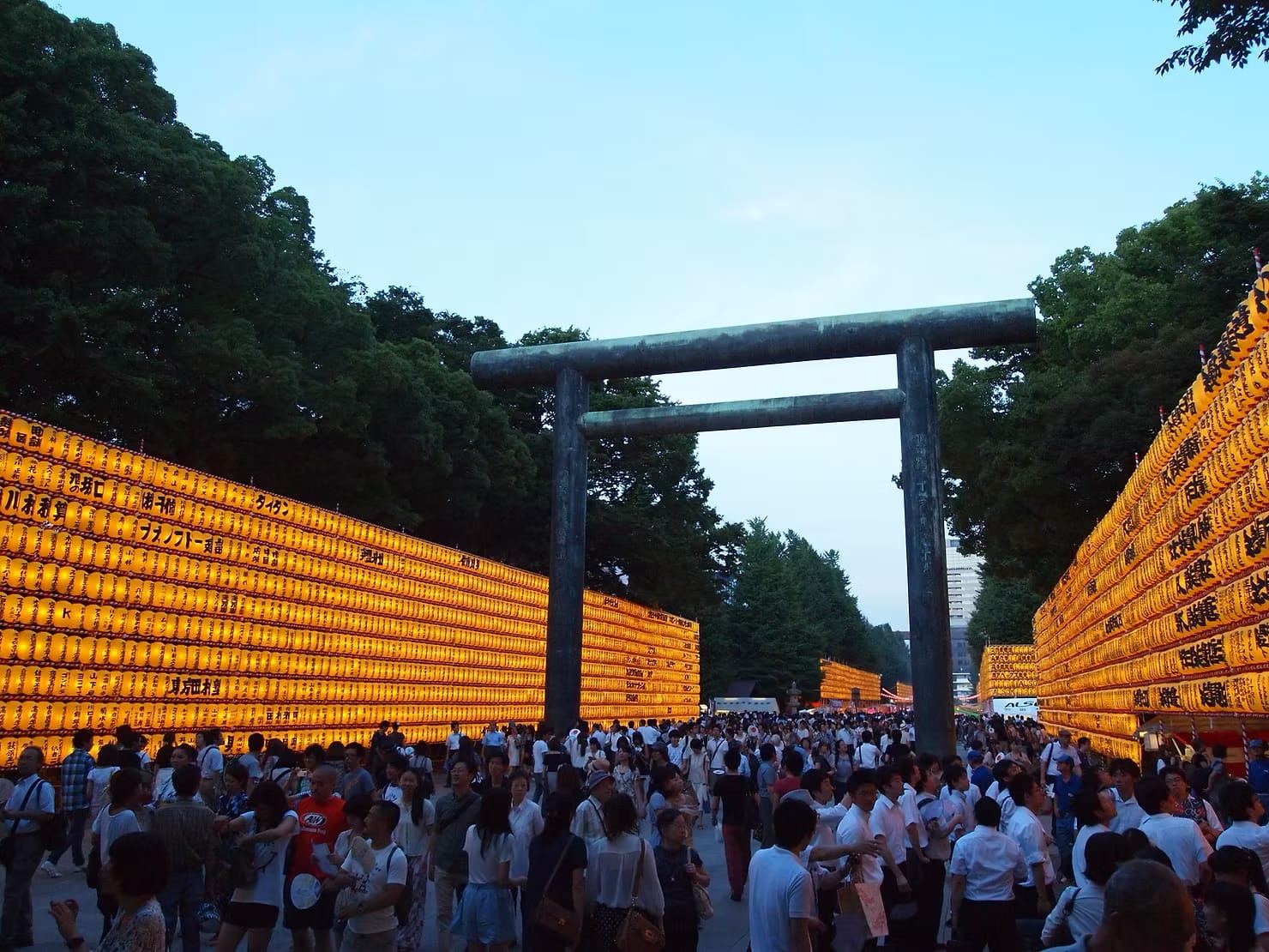 A crowd walking towards the entrance of a shrine surrounded by lanterns in Tokyo, Japan
