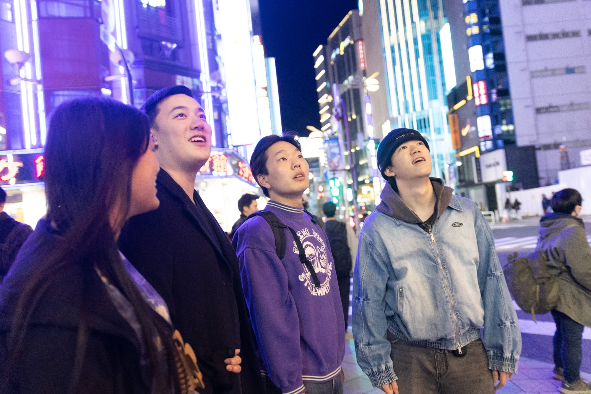 A tour guide and their guests gaze up at Tokyo's neon night