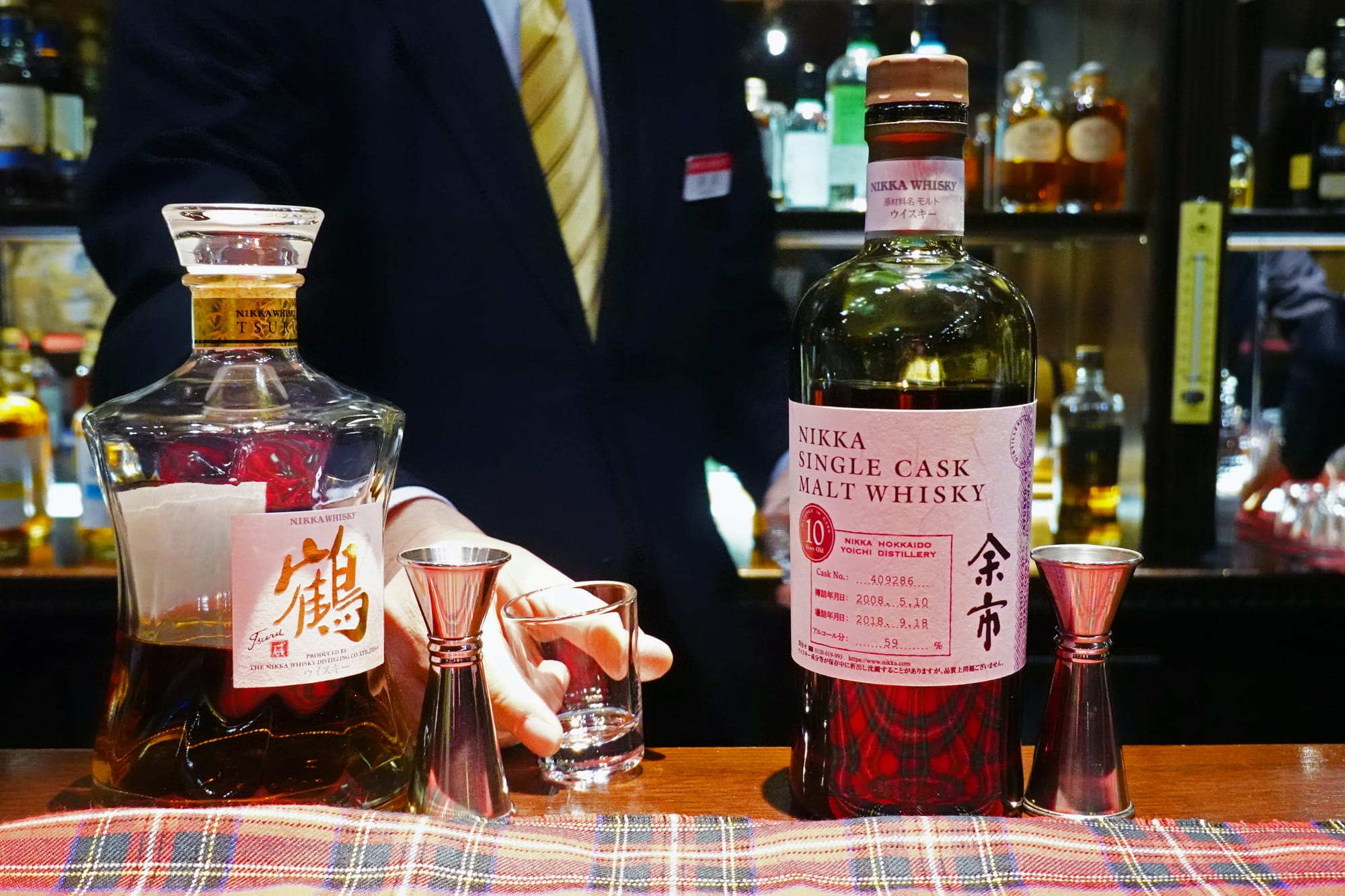 A bartender preparing two whisky drinks at a bar in Japan