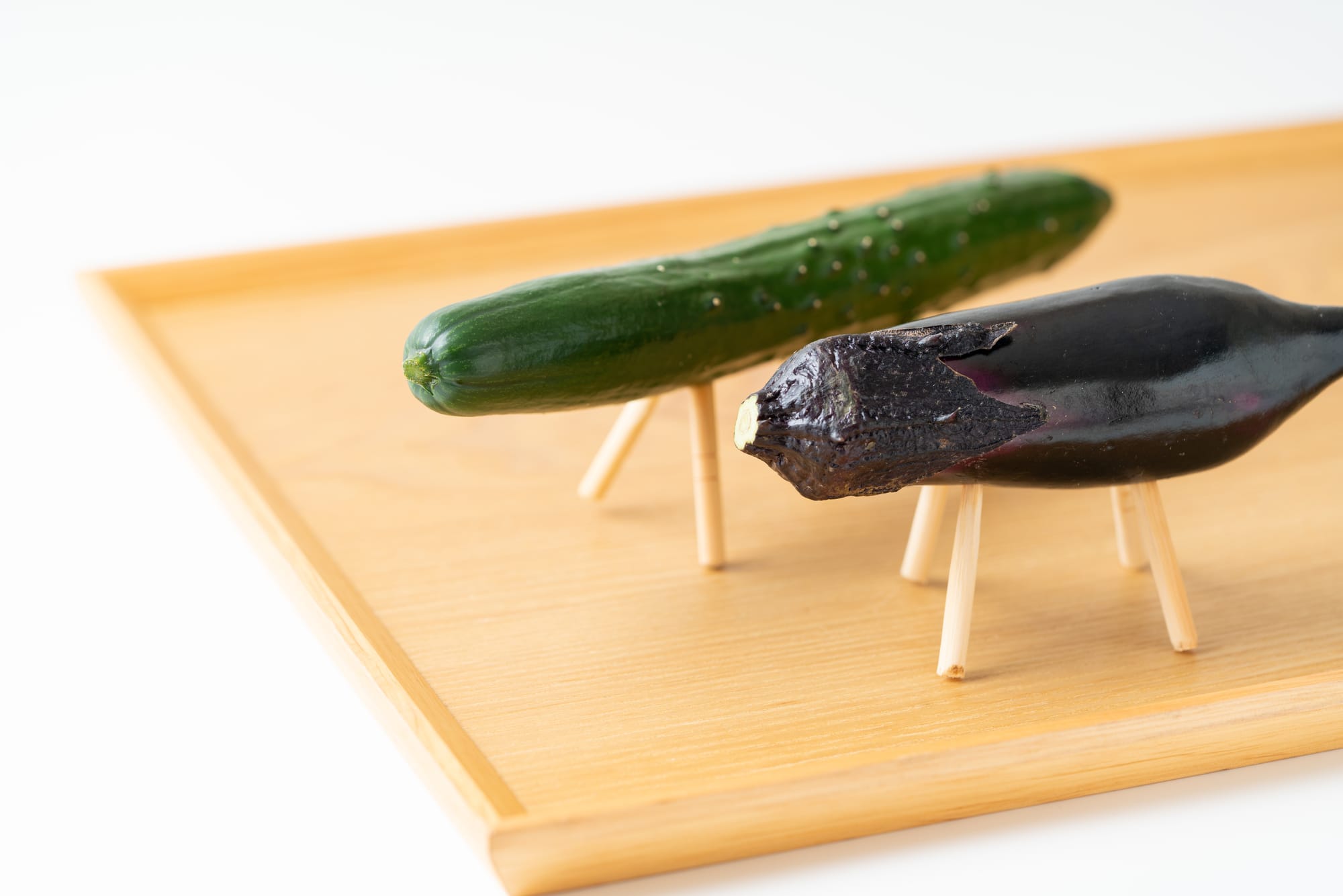 A cucumber and an eggplant propped up on sticks, representing a horse and a cow as per the Japanese obon tradition.