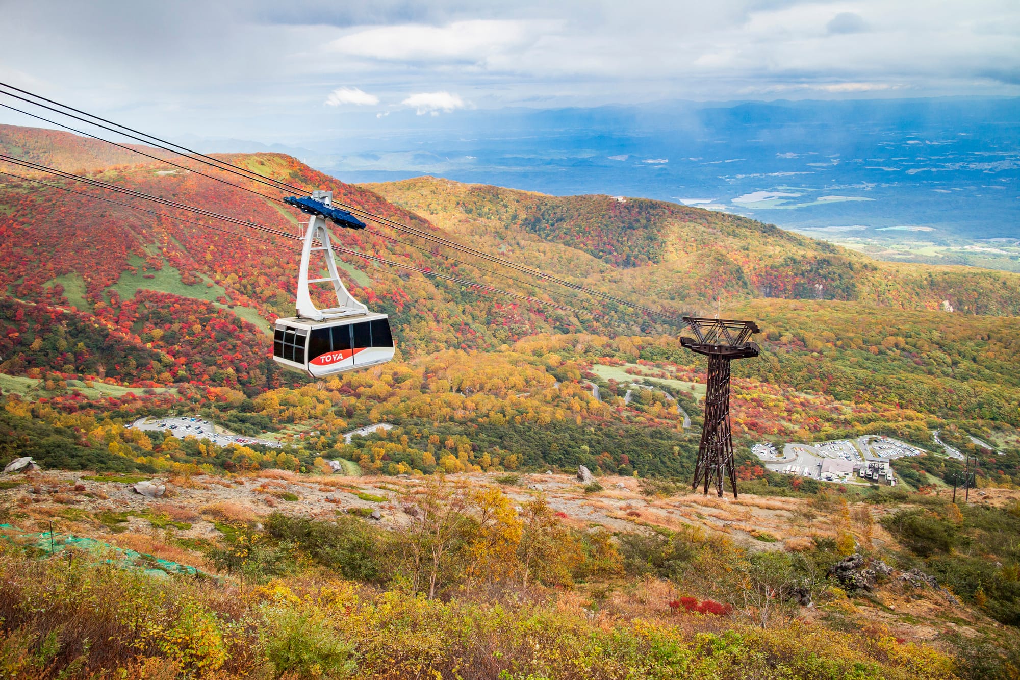 A ropeway makes its way up an autumn foliage covered mountain in Japan.