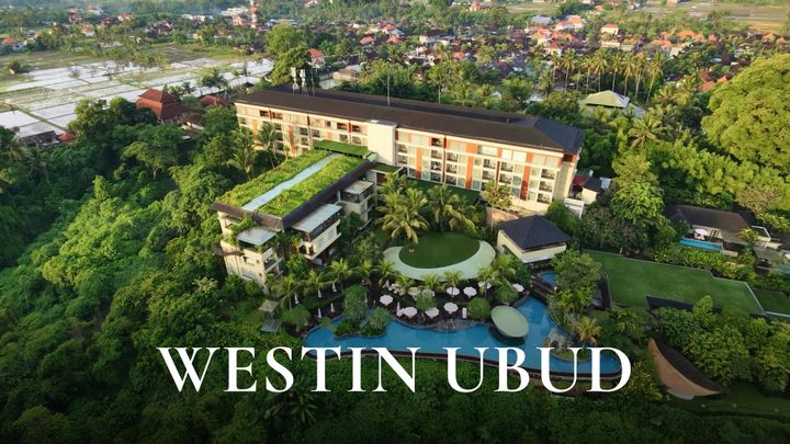 Aerial drone view of The Westin Resort & Spa Ubud surrounded by dense green forest and rice fields with WESTIN UBUD text overlay