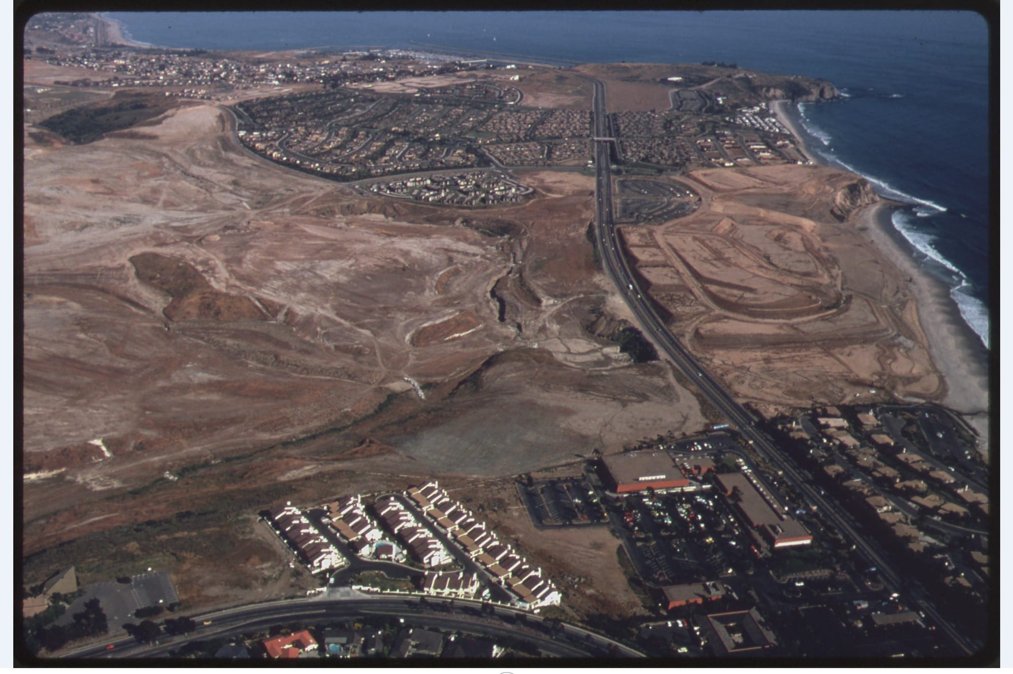 aerial view of coastal development; open space between housind developments along an ocean coast