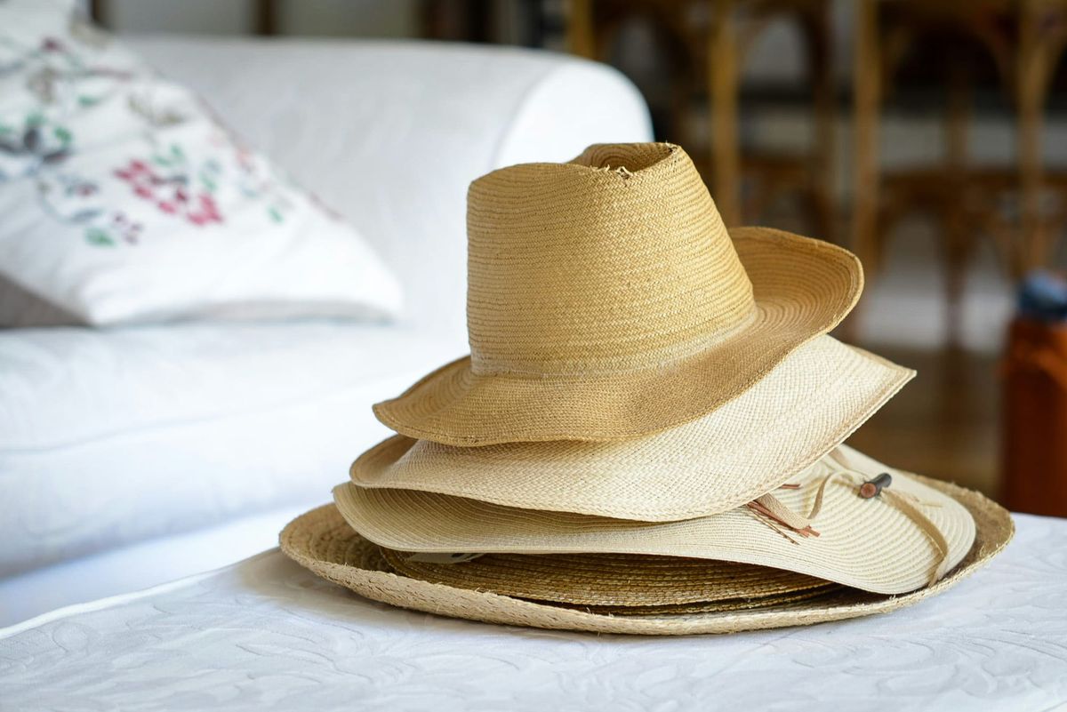 Stack of straw hats on a white ottoman.