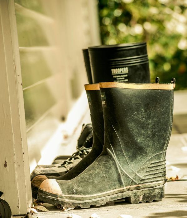 Dirty rain boots placed outside of a door.
