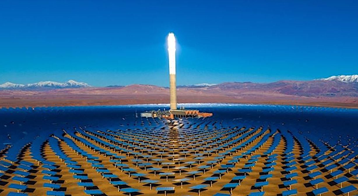 A glowing tower amid a semicircular array of mirrors in the desert, snow-capped mountains behind