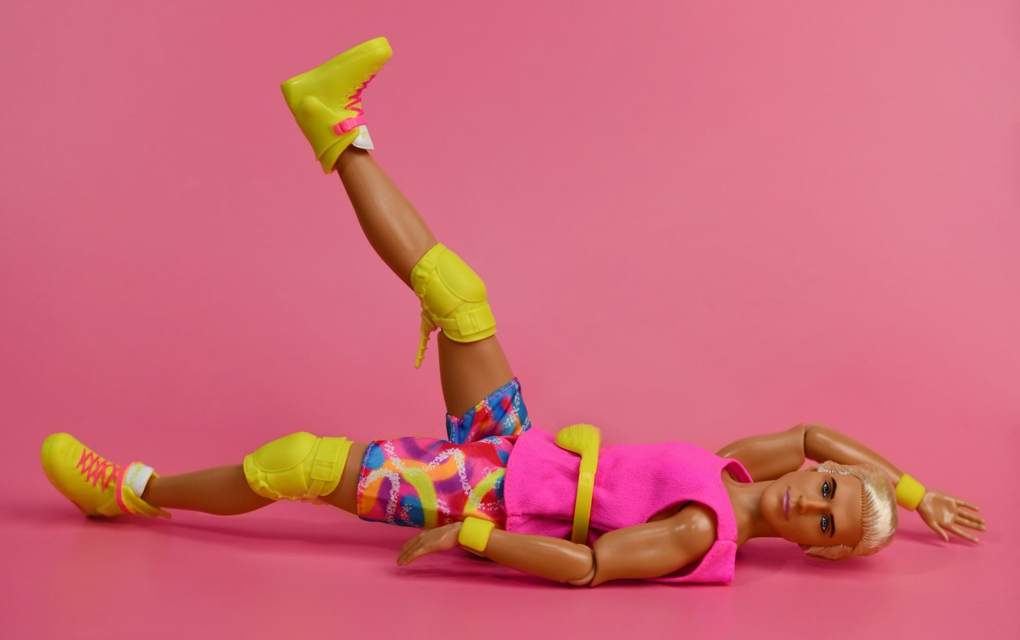 Doll in colorful athletic wear on pink background