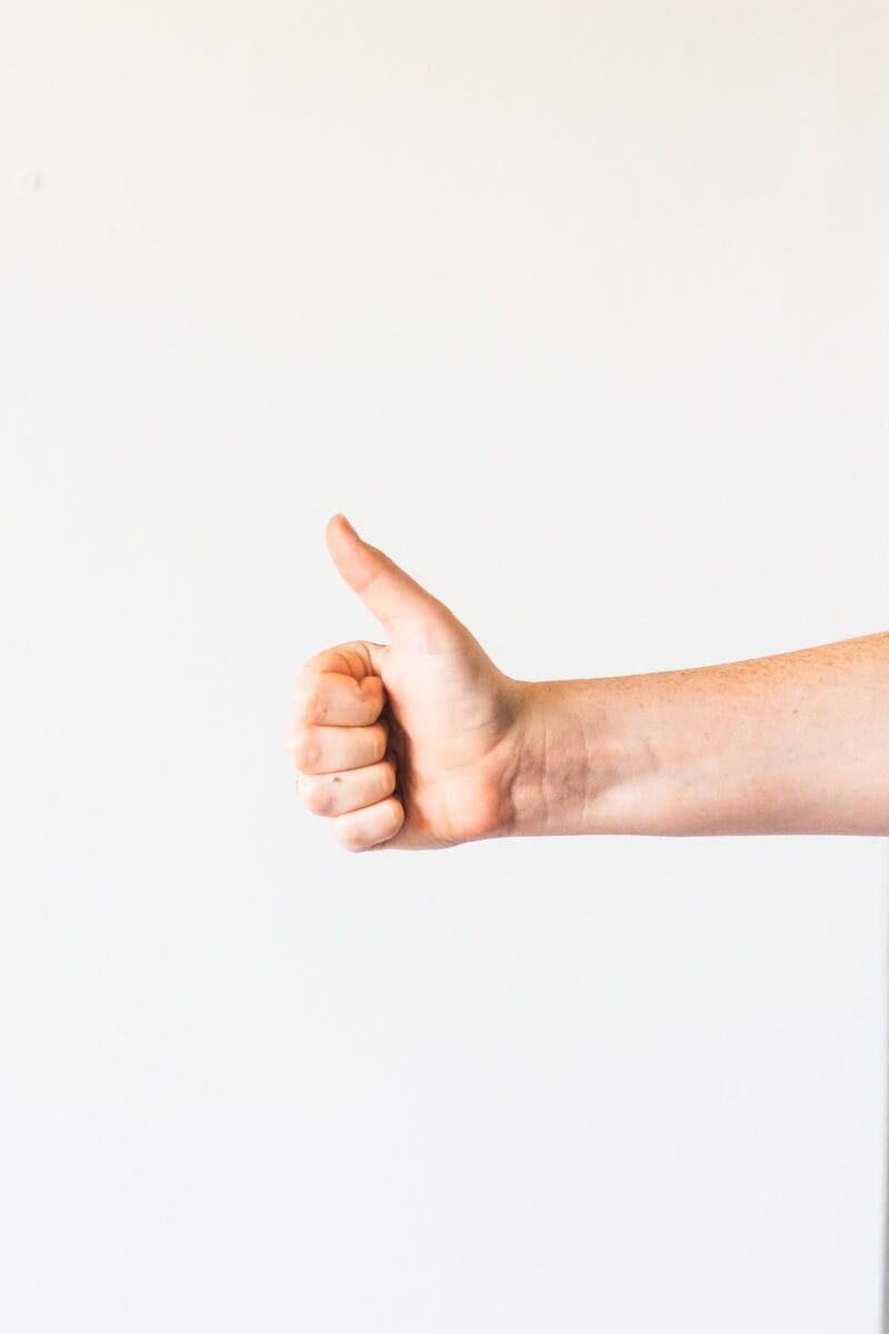 persons right hand doing thumbs up