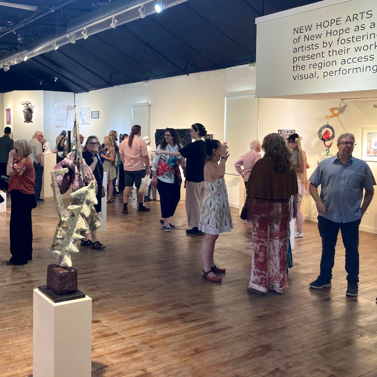 a group of people mingling in a gallery full of art