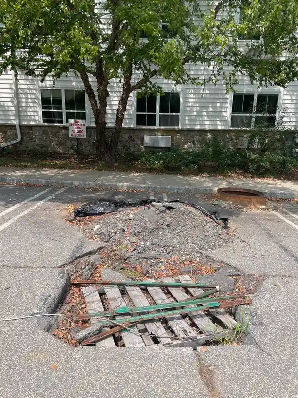a hole in the asphalt that spans two parking spaces