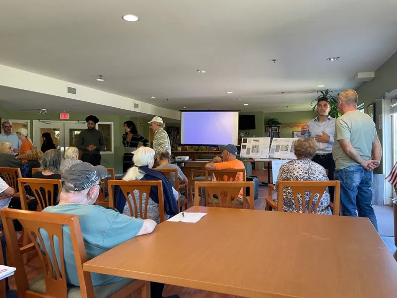 senior citizens sit and stand as CIS employees answer questions in the community room
