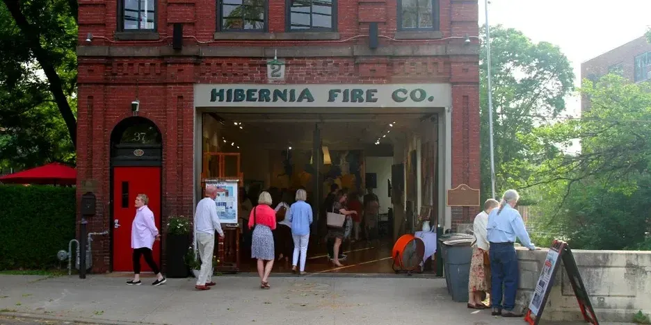 people looking at art inside the garage of a old firehouse