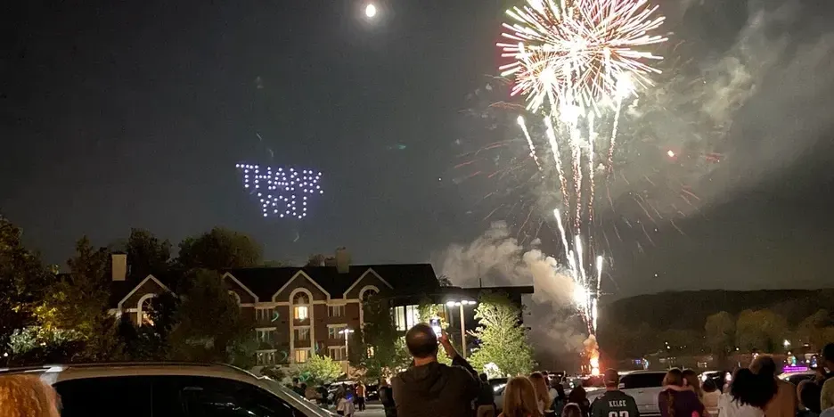 fireworks exploding over the river while a drones spell out "thank you"