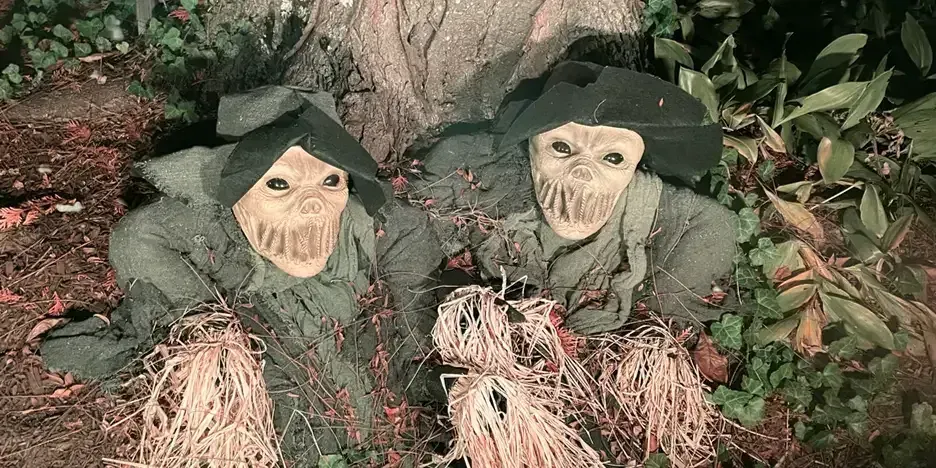 two scary figures crawling out from under a tree root