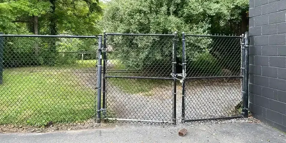 a chain link fence with the gate closed and locked with a chain and padlock