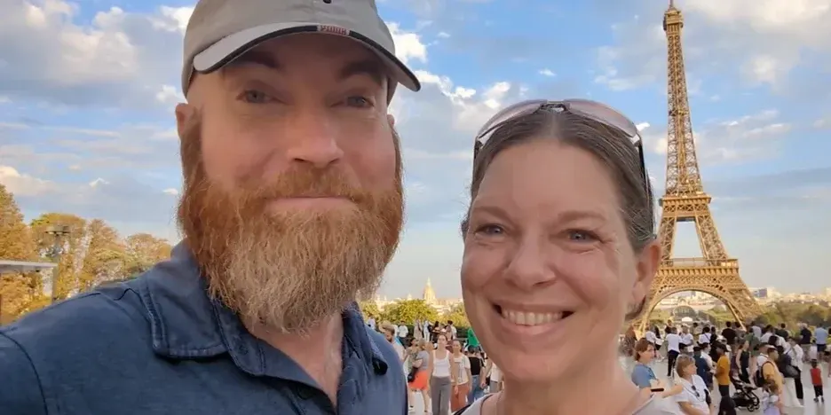 a smiling couple standing by the Eiffel Tower