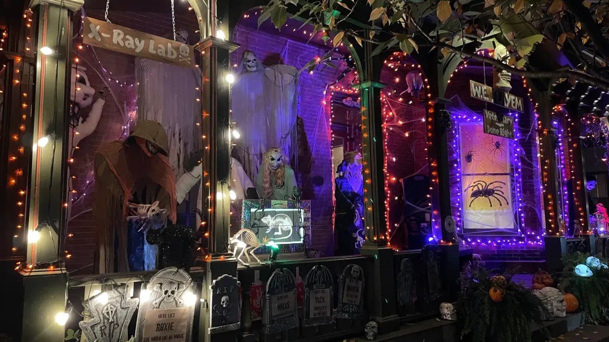 a house decorated with skeletons and tombstones, as well as orange and purple string lights