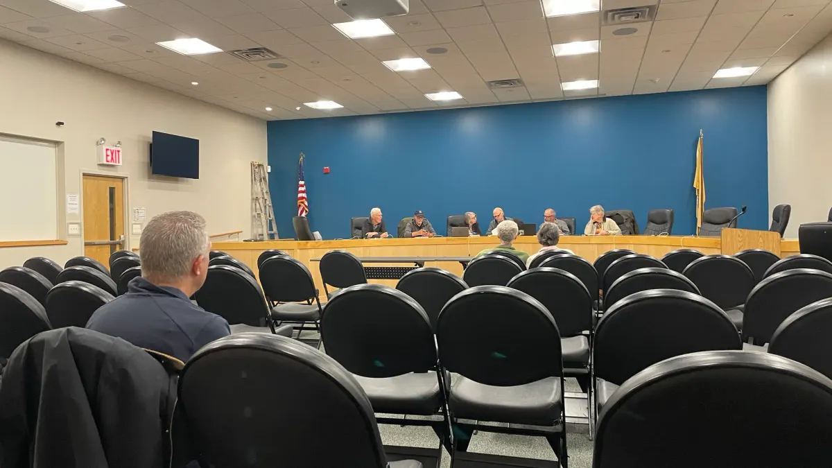 a group of board members sit at the dais and several resident sit in the audience