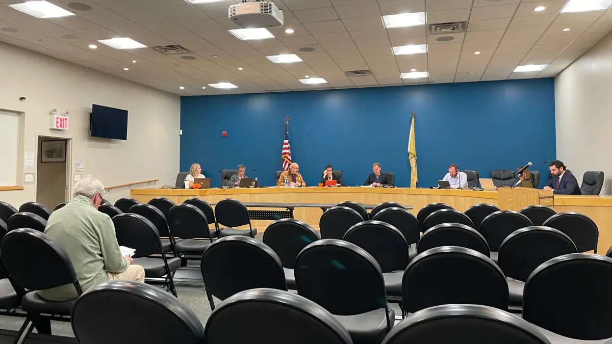 eight people sitting at the dais and one person sitting in the audience at the meeting
