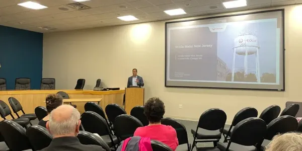 a man standing in front of a podium, speaking to a small audience