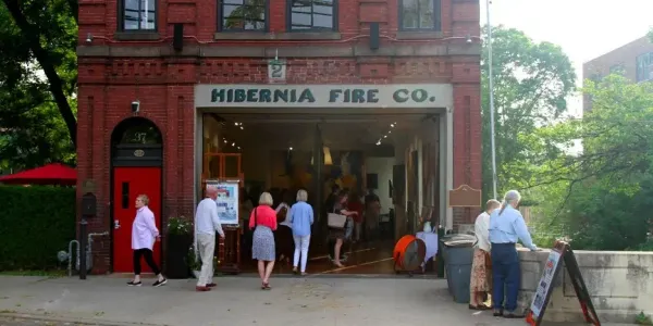 people looking at art inside the garage of a old firehouse