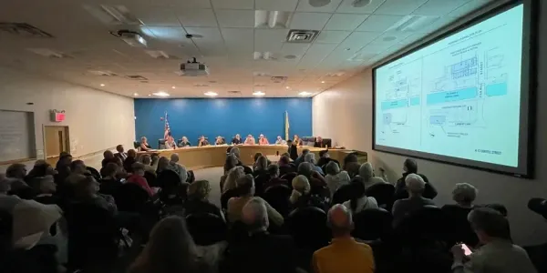 a room filled with people sitting and looking at a slide projected on a screen