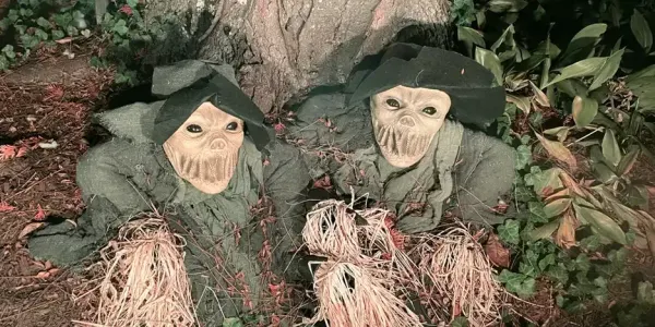 two scary figures crawling out from under a tree root