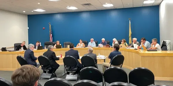 a group of men sit at the table before the Planning Board