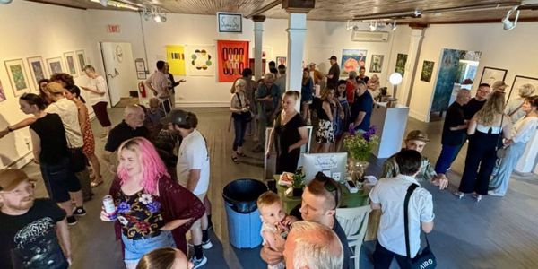 a crowd of people mingle and look at art inside of an art gallery