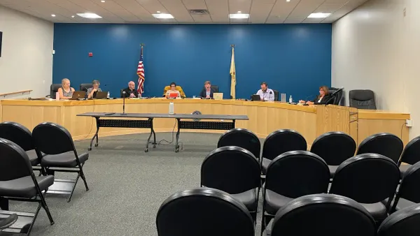 a group of council members sitting in their places behind the dais