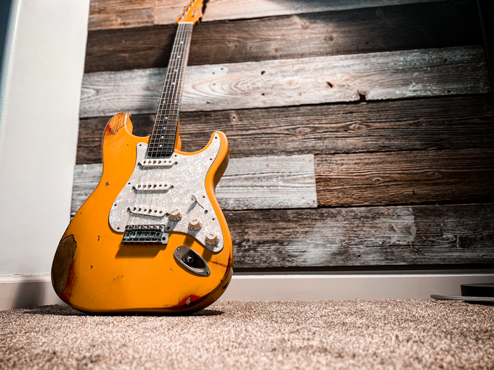 A yellow Stratocaster style custom guitar with a relic finish by JTal Guitars in Elkhorn, Nebraska