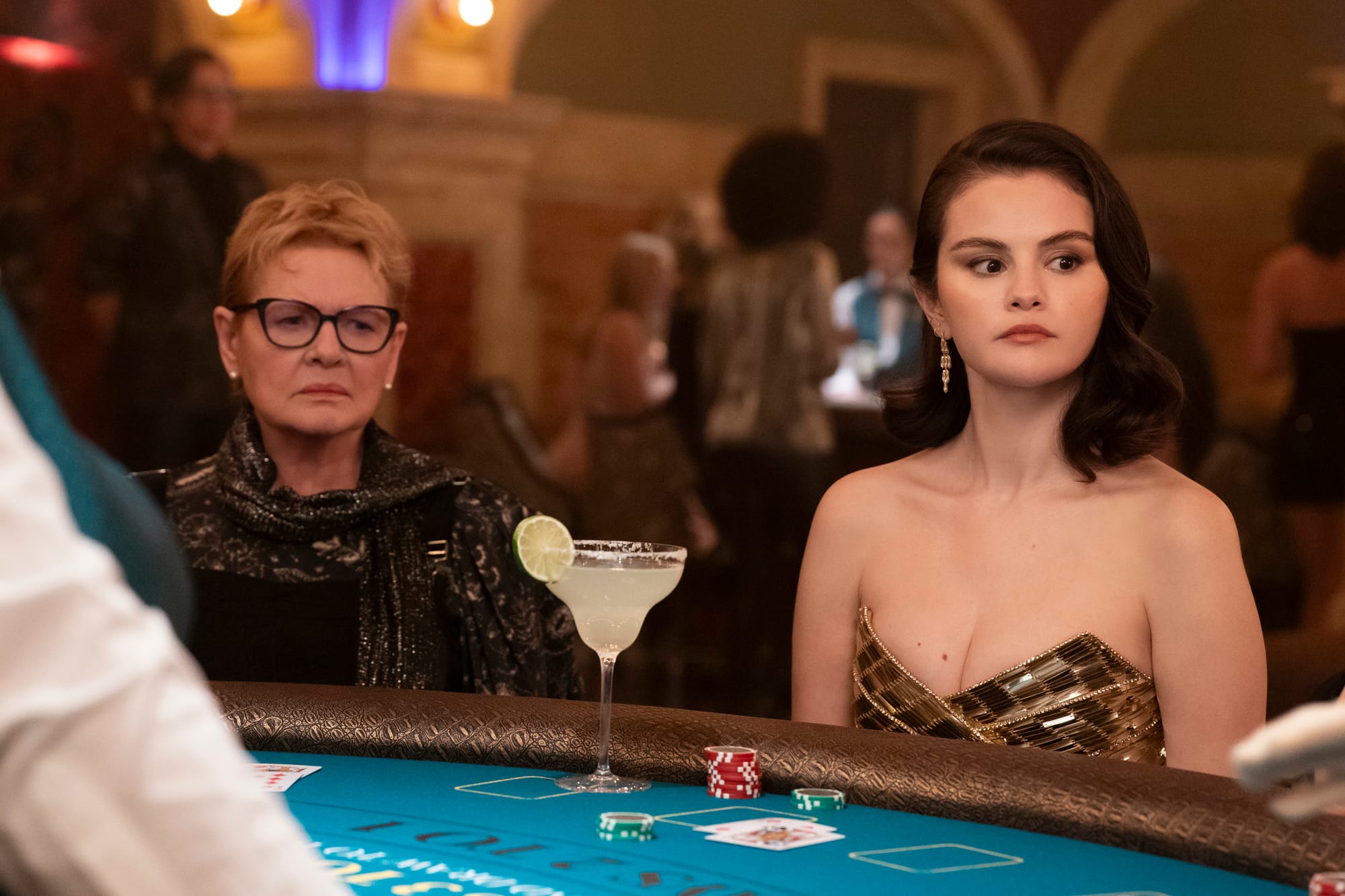 Dianne Wiest and Selena Gomez seated at a card table with a margarita between them.