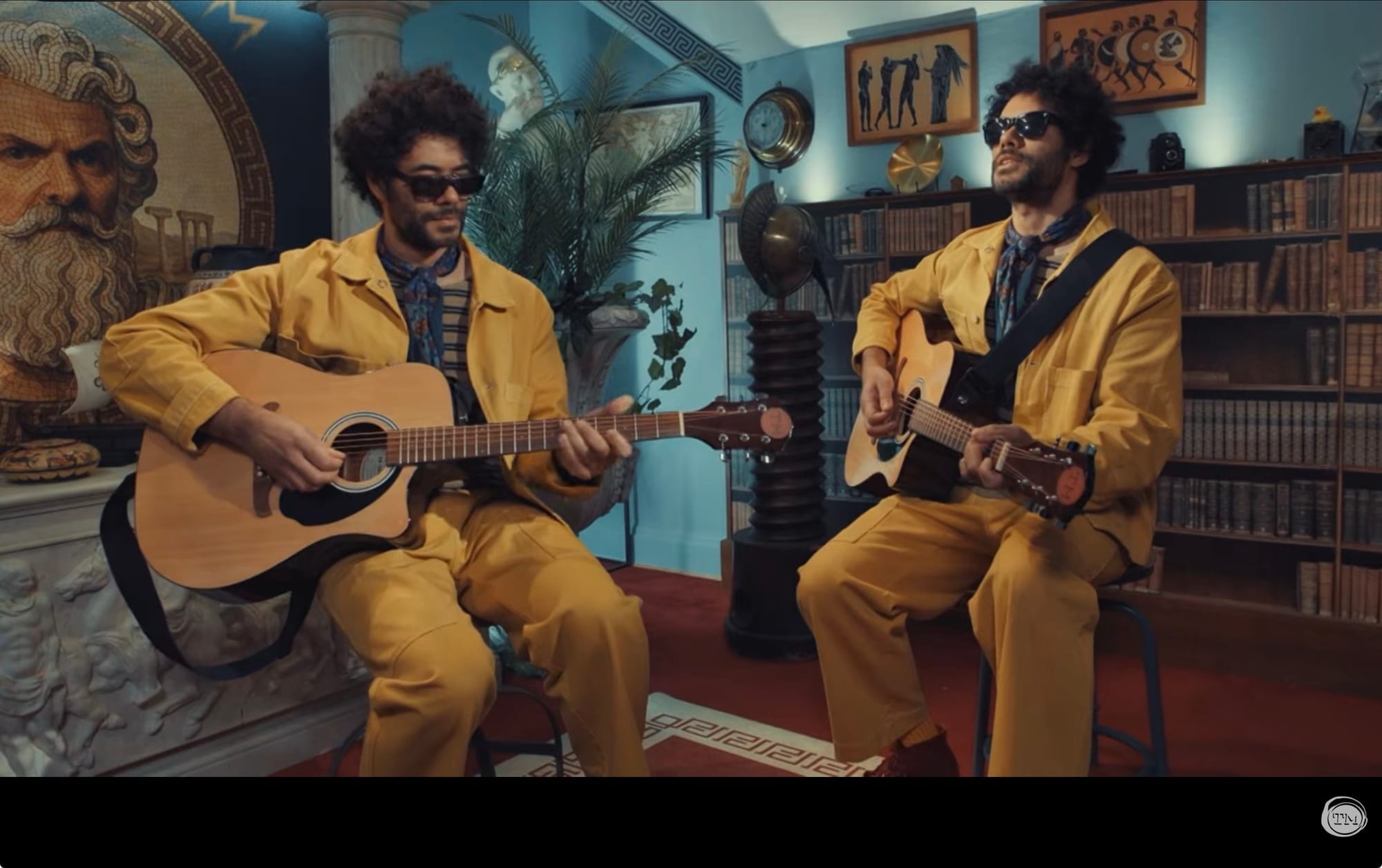Two Richard Ayoades each play the guitar, wearing sunglasses.