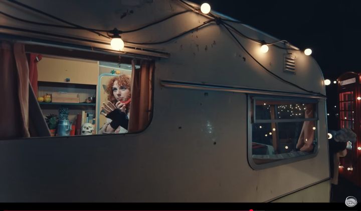 Ania Magliano on a red telephone inside the Taskmaster caravan at night.