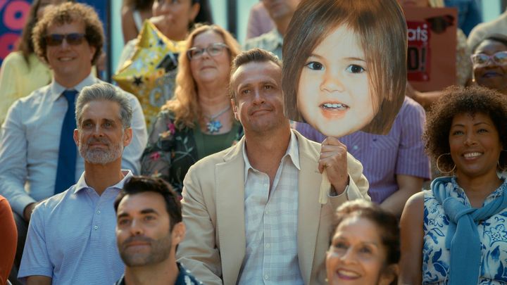 Jason Segel holds a large cutout photo of a kid, who I can only assume is young Lukita Maxwell