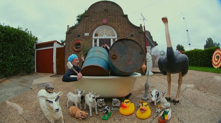 Little Alex Horne in a clawfoot bathtub, covered in barrels and surrounded by plastic farm animals