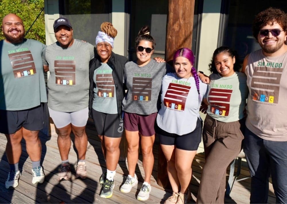 A group of people in running clothes standing together outside on a deck in front of a building
