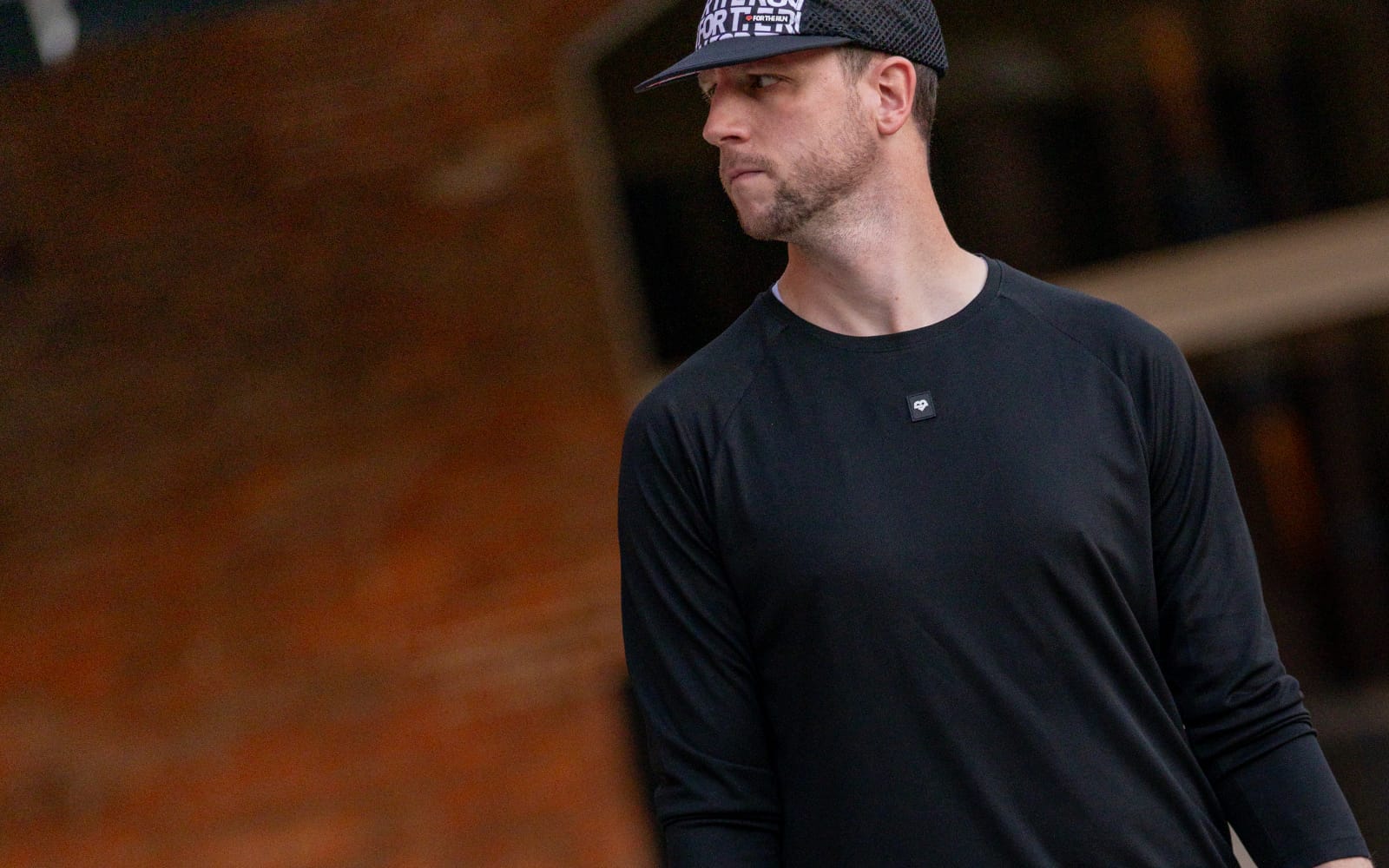 A man in a black t-shirt and hat looking to his left