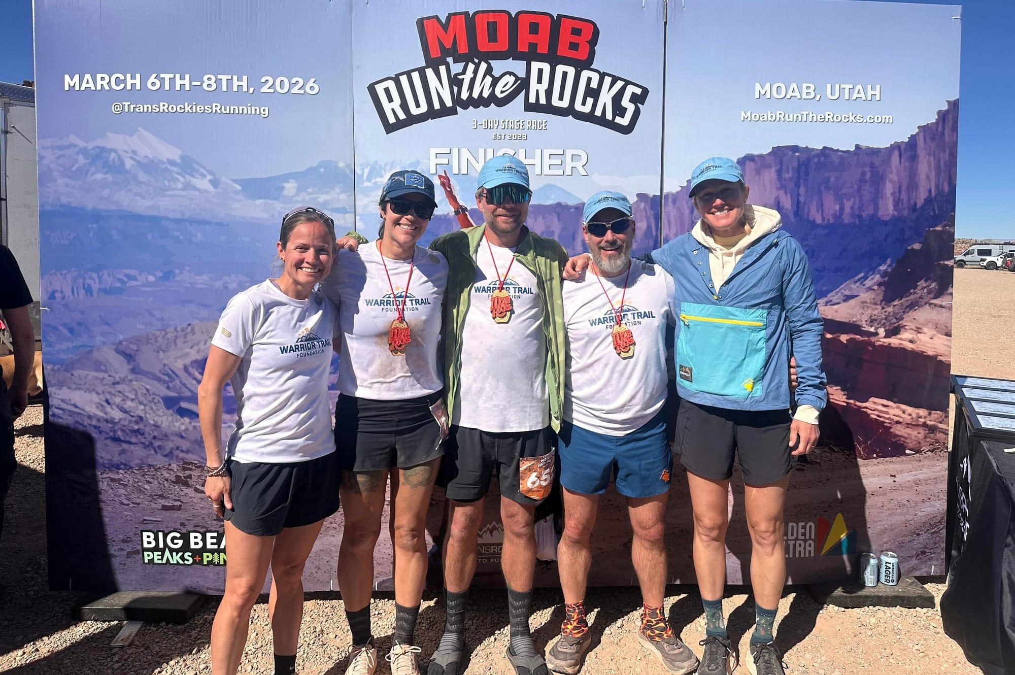 A group of runners posing together in front of a race banner