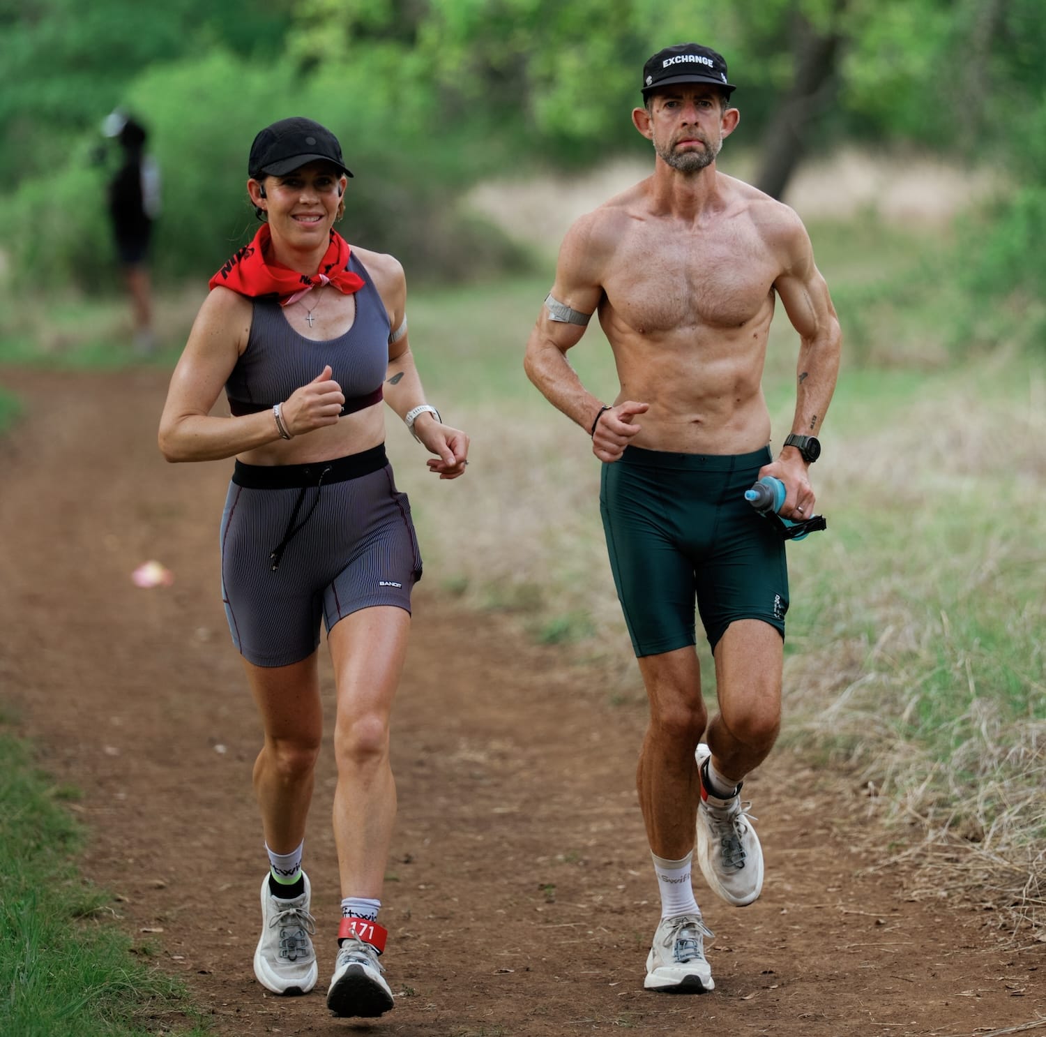 A man and a woman running on a dirt trail side-by-side
