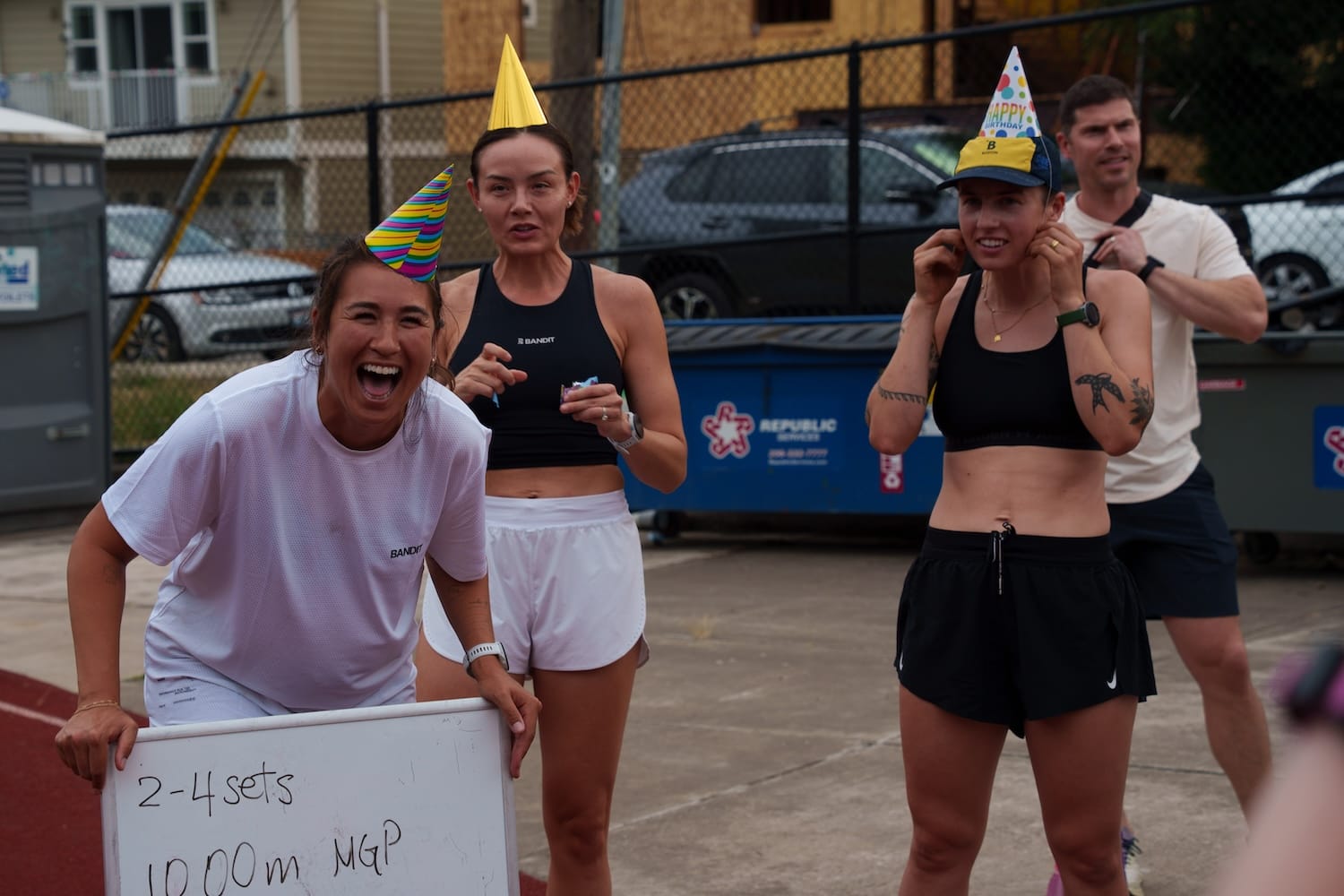 Three woman in running apparel and birthday hats standing outside