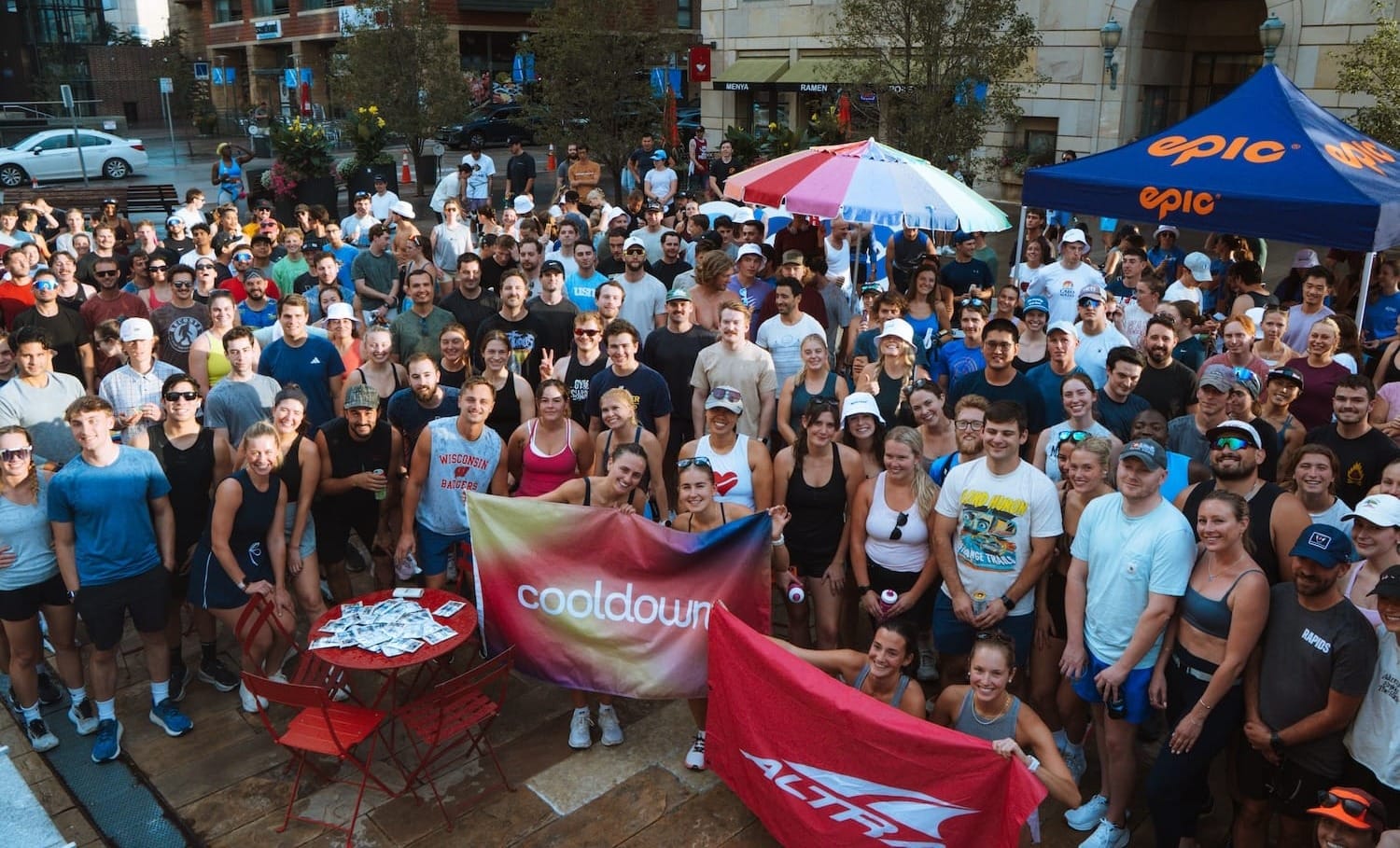 A large group a runners posing for a photo outside while holding a couple of brand banners